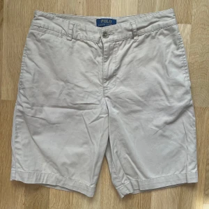Beige shorts från Polo Ralph Lauren - Klassiska beige chino shorts från Polo Ralph Lauren med normal passform. Storlek 14 vilket motsvarar ca XXS/XS. 10/10 skick✅ Hör av vid funderingar.