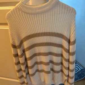  tröja från Gina Tricot - Supermysig stickad tröja från Gina Tricot i storlek XS. Tröjan är vit med breda beigea ränder, har en ribbad struktur och lång ärm. Perfekt för lager-på-lager och chill dagar. Snygg till både jeans och kjol!