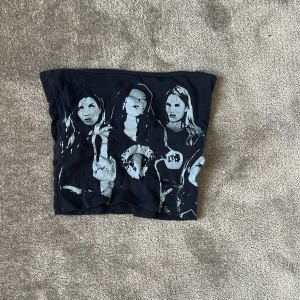 Mörkblå tubtopp med tryck av tjejer - Cool mörkblå tubtopp med ljusblått tryck av flera tjejer på framsidan. Toppen är axelbandslös och har en rak bandeau-form. Perfekt att styla med jeans eller kjol för en edgy look. Det finns ingen lapp så jag vet inte var dem är ifrån eller storlek men skulle tippa på xs 