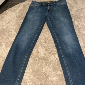 Blå jeans Jack & Jones Regular Clark - Snygga blå jeans från Jack & Jones, modell Regular Clark. Klassisk femficksdesign med raka ben och normal passform. Jeansen har en mellanblå tvätt med lätt slitning och detaljerade sömmar. Perfekta för en avslappnad och stilren look. Använd få gånger max 3 gånger kan sänka pris vid snabb affär 