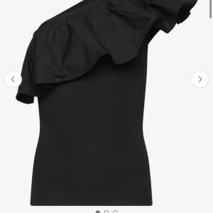 Svart oneshoulder topp med volang - Snygg svart oneshoulder topp med volangdetalj över axeln. Storlek 170-176 men skulle säga den sitter som en xs-S