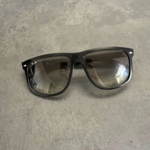 Svarta Ray-Ban boyfriend solglasögon - Klassiska svarta Ray-Ban boyfriend solglasögon med bred båge och mörktonade glas. Snygg och tidlös modell som passar till allt. Ray-Ban-loggan syns tydligt på båda sidorna. Perfekta för att ge din stil en cool edge.
