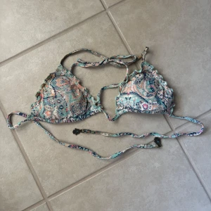 Mönstrad bikiniöverdel med volang - Supersöt bikiniöverdel med paisleyinspirerat mönster i blått, rosa och beige toner. Triangelformade kupor med volangkant och smala knytband både i nacken och runt ryggen. Perfekt för stranden eller poolen!