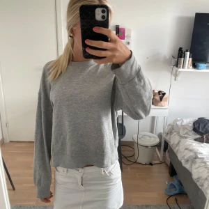 Grå basic sweatshirt med loose fit - Enkel och stilren grå sweatshirt med rund hals och långa ärmar. Tröjan har en loose passform och är tillverkad i mjuk bomullsmix, perfekt för chill dagar. Ribbstickade muddar vid ärmslut och nederkant ger en klassisk look.