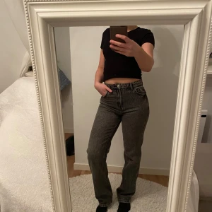 Grå jeans med hög midja - Snygga grå jeans med hög midja och klassisk femficksdesign. De har en rak passform och är perfekta för en avslappnad stil. Jeansen har en dragkedja och knapp framtill.