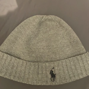 Grå Ralph lauren mössa  - Säljer en helt ny Ralph lauren mössa som jag fick i julklapp. Otroligt stilig och till ett väldigt bra pris för att vara helt ny 