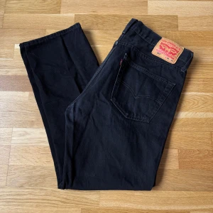 Levis 501 Svarta Jeans - Levis jeans i modellen 501 och färgen svart. Storlek: 34 W, 30 L, Midja: 44.5 cm Ytterben: 101.5 cm Benöppning: 21.5 cm Material: 100% Cotton.