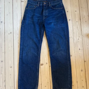 Blå jeans från Nudie Jeans - Säljer ett par klassiska blå jeans från Nudie Jeans. De har en rak passform och är tillverkade i slitstarkt denim. Perfekta för en avslappnad stil med fem fickor och knappgylf. Jeansmodell: Tuff Tony