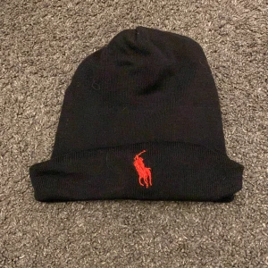 Svart mössa från polo Ralph lauren - Snygg svart mössa från polo Ralph lauren. Perfekt för att hålla värmen under kyliga dagar. Enkel och stilren design som passar till det mesta. Pris kan diskuteras vid snabb affär.