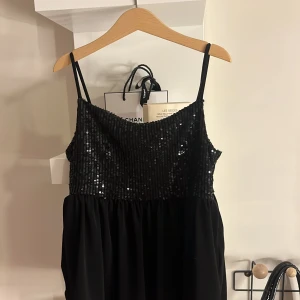 Svart paljetttopp från Gina Tricot - Snygg svart topp från Gina Tricot med glittriga paljetter upptill och smala axelband. Perfekt för en festlig kväll! ✨Använd en gång 💘