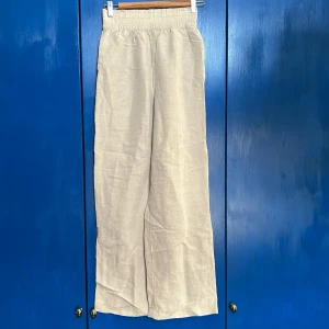 Beige linnebyxor från H&M - Säljer ett par bekväma beige linnebyxor från H&M. Byxorna har en elastisk midja för extra komfort och en avslappnad passform.  Lite halvt utsvänga ben, med fickor. Super sköna på sommaren☀️