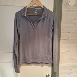 Grå långärmad tröja från Energetics - Säljer en grå varm långärmad tröja från Energetics med halv dragkedja framtill. Perfekt för löpning när det är lite kyligt ute!jag.