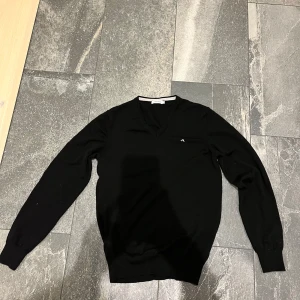 Svart tröja från J.Lindeberg - Snygg svart tröja från J.Lindeberg med v-ringning och diskret logga på bröstet. Perfekt för en stilren look. Nypris 1500