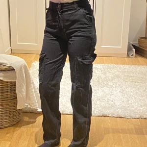 Svarta cargobyxor - Snygga svarta cargobyxor med två fickor. Storlek 34 Har dragkedja och knapp fram. Älskar dem men tyvärr för små för mig nu. Är 173 cm för jämförelse 