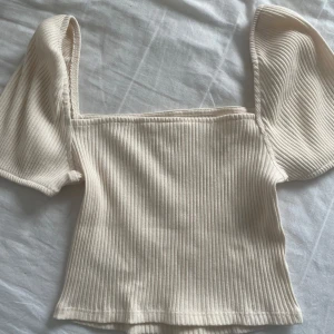 Beige ribbad topp -  Beige ribbad topp från hm. Toppen har en fyrkantig halsringning. Nyskick! 