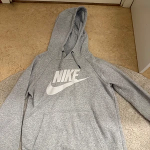 Grå hoodie från Nike - Säljer en klassisk grå hoodie från Nike med stor vit logga på bröstet. 