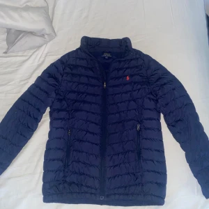 Blå pufferjacka från Ralph Lauren  - Snygg Mörkblå polo raphl lauren jacka i storlek L, den är helt perfekt till våren och hösten och den är helt defekt fri inga skador eller fläckar. Pris kan diskuteras om du kontaktar mig. Ny jacka kosta runt om 2000kr