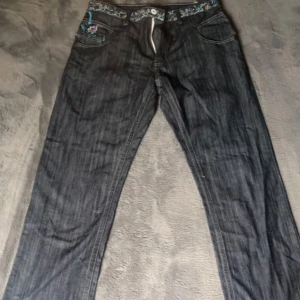Artful dodger jeans - Jeans med överfet broderitryxk i storlek 34 Tyvärr är dragkedjan trasig men om du kan laga den så är dom i toppskick inget tecken på användning förutom dragkedjan