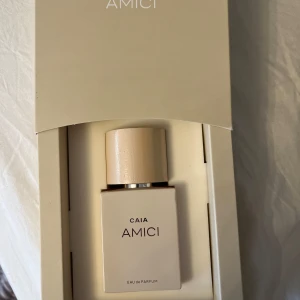 Parfym CAIA Amici - Elegant parfym från CAIA med namnet Amici. Flaskan är stilren och fyrkantig i en ljus beige nyans med matchande kork. Förpackningen är också i samma ljusa ton, vilket ger ett lyxigt intryck. Perfekt för den som söker en sofistikerad doft. Bara testad en gång 