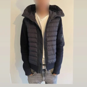 Moncler cardigan  - Säljer en snygg svart dunjacka från Moncler med quiltad design och dragkedja. Jackan har långa ärmar och en praktisk huva. Perfekt för kyligare dagar med stil. Moncler-logga på ärmen ger en exklusiv touch. Tänkt mig runt 4500 kr storlek M. Givetvis är jackan äkta inga konstigheter med den. Har kvitto någonstans på Mail 
