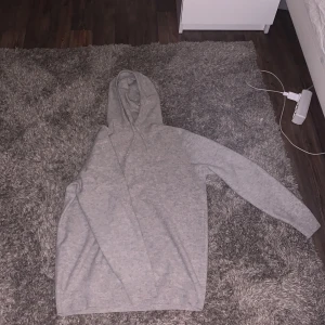 Grå merino/Cashmere hoodie - Säljer en mysig grå cashmere hoodie perfekt för kyliga dagar. Den har en klassisk design med huva och långa ärmar. Materialet är mjukt och bekvämt, vilket gör den idealisk för avslappnade tillfällen. Passar bra till jeans eller mjukisbyxor.