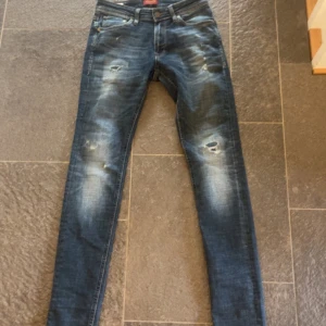 Mörkblå Jack and Jones jeans - Säljer nu mina Jack and Jones jeans med snygga slitningar och mycket fade. Byxorna är i ny skick använda typ 5 gånger. Dem sitter slim/skinny. Modellen är 180 och väger 65. skriv för frågor och liknande.