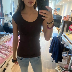 Brun tight topp - Säljer en stilren brun topp med tight passform. Toppen är ärmlös och perfekt för en enkel och snygg look. Passar bra till jeans eller kjol. Perfekt basplagg i garderoben! 
