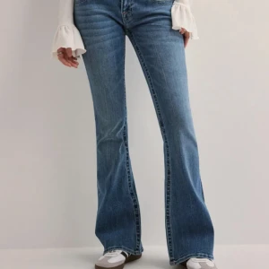 Blå bootcut jeans från True Religion - Snygga blå bootcut jeans från True Religion med märkets ikoniska broderi på bakfickorna. Jeansen har en lågmidjad passform och är från kollektionen med Nelly. Knappt använda, storlek 28 och nypris är 1399kr💞 