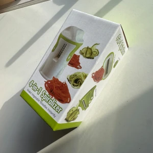 4-i-1 Spiralizer - Praktisk 4-i-1 spiralizer för att enkelt göra grönsaksnudlar. Perfekt för att skapa hälsosamma och kreativa måltider med olika grönsaker. Kompakt design i vitt och grönt.