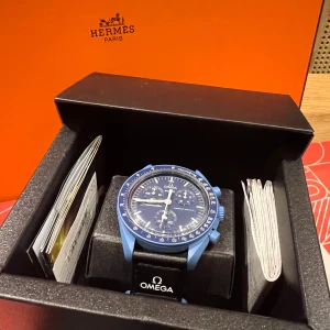 Blå Omega Speedmaster MoonSwatch - Säljer en stilren Omega Speedmaster MoonSwatch i en snygg blå färg. Klockan har en detaljerad urtavla med flera funktioner och kommer i originalförpackning. Perfekt för den som vill ha en kombination av klassisk design och modern stil.kvitto och allt og
