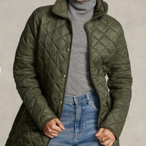 Olivgrön quiltad jacka från Polo Ralph Lauren - Snygg olivgrön quiltad jacka från Polo Ralph Lauren. Jackan har en klassisk krage och stängs med tryckknappar. Den är vattenavvisande och perfekt för kyligare dagar. Två praktiska fickor framtill ger extra funktionalitet. Nypris 4 490 kronor, inköpt på Pondus.