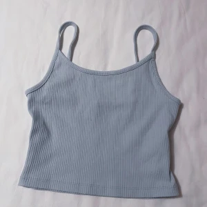Ljusblått linne - Säljer en söt ljusblå ribbad linnetopp från FB Sister. Toppen har smala axelband och en croppad passform. Stretchigt material. Liten fläck (kolla sista bilden). Kontakta mig om du har frågor☺️
