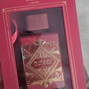 Lattafa Badee Al Oud Sublime parfym - Lyxig parfym från Lattafa, Badee Al Oud Sublime, i en elegant röd flaska med guldiga orientaliska detaljer. Kommer i matchande röd presentask med spegel och folder. Flaskan har en fyrkantig form och exklusiv design som verkligen sticker ut.