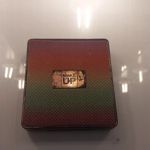 Make Up ögonskuggspalett 9 nyanser - Säljer en fyrkantig ögonskuggspalett från Make Up med 9 olika nyanser i bruna, beige och guldiga toner. Paletten har spegel i locket och ett snyggt fodral i gradient från rött till grönt. Perfekt för att skapa både matta och skimrande looks. Den är lite sliten på locket❤️❤️