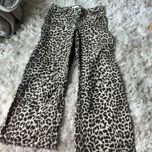 Leopardmönstrade wide byxor - Snygga byxor med leopardmönster i beige och svart. Modellen är wide med raka ben och klassisk femficksdesign. I strl 36 från H&M. Inköpta i mars 2025 och använda 2 gånger.