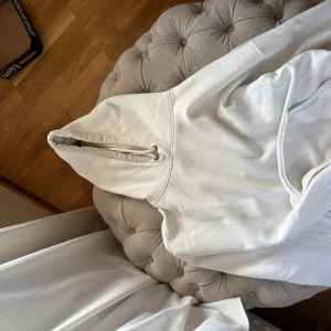 Vit hoodie från BikBok med huva - Säljer en stilren vit hoodie från BikBok i storlek S. Tröjan har klassisk huva med snörning och är gjord i mjukt material som känns skönt mot huden. Perfekt för dig som gillar en enkel och clean look.