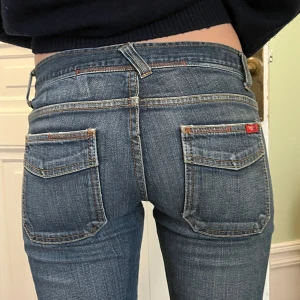 Blå jeans med stora fickor - Snygga blå jeans med stora fickor fram och bak, låg midja och raka ben. Jeansen har klassiska kontrastsömmar och en cool vintagekänsla. Perfekta för dig som gillar en avslappnad men ändå trendig look.