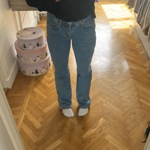 Low straight jeans från bik bok blå - Säljer ett par blåa jeans från bik bok i modellen low straight . De har låg midja, raka ben och klassisk femficksdesign. Jeansen är i 100% bomull och har snygga kontrastsömmar samt en brun patch bak i midjan.