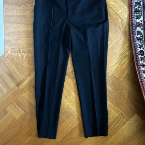 Svarta kostymbyxor från Filippa K (Capri byxa) - Snygga svarta kostymbyxor från Filippa K i klassisk rak modell. En skön och dressad känsla. Perfekta för en clean och stilren look.