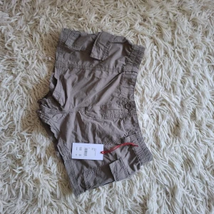 Beige cargoshorts med fickor, S - Snygga beige cargoshorts från H&M i bomull med flera praktiska fickor och elastisk midja. Perfekta för varma dagar och chill stil. Klassisk design med knapp och dragkedja framtill. Passar dig som gillar avslappnat och funktionellt.