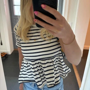 Randig volangtopp från Zara - Topp från Zara med marinblå och vita ränder. Modellen har kort ärm, rund hals och en volang nedtill. Toppen är i fint skick!😊