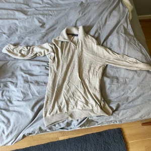 Beige half zip tröja Jack & Jones - Snygg beige stickad tröja från Jack & Jones med half zip och hög krage. Tröjan har lång ärm och ribbade muddar vid ärmslut och nederkant. Perfekt för lager-på-lager och chill stil.