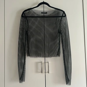 Svart nättopp från Stradivarius - Säljer en svart nättopp, broderad med ädelstenar. Helt ny i skick, perfekt för snygga överklädnader och fester.