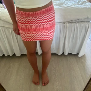 Rödvit Missoni kjol med zigzag-mönster - Säljer en kort kjol från Missoni i storlek M med ikoniskt rödvitt zigzag-mönster. Kjolen är figurnära och sydd i mjuk bomullsmix med lite stretch för skön passform. Notera att den är lite uppvikt på första bilden