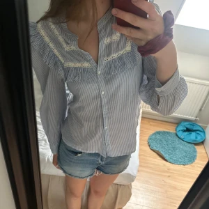 Blåvit randig blus med volang - Supersöt blåvit randig blus med volangdetaljer. 