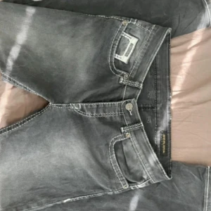 Grå jeans från Behype Denim - Säljer ett par grå lågmidjade jeans från Behype Denim med tydliga vita kontrastsömmar och snygga bakfickor. Jeansen har cool tvättad look. Perfekta för dig som gillar streetstyle och vill sticka ut lite extra. Dom är aldrig använda då dom tyvärr inte passade mig i midjan! Det är ingen vanlig dragkedja utan det är knappar! De är i väldigt bra skick! Strl: W33 L32. Midjemått ca 42cm, innerbenslängd ca 79cm, total längd ca 103cm! 