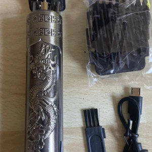 Trimmer - Snygg hårtrimmer i metall med detaljerat drakmönster. Kommer med flera kammar, rengöringsborste och USB-laddare. Perfekt för att fixa skarpa linjer och detaljer. Blad i rostfritt stål och keramik för extra precision.