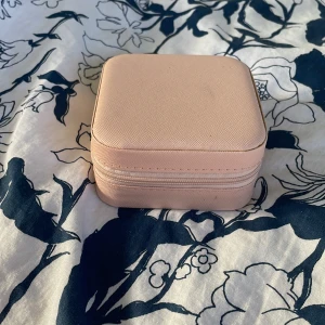 Rosa smyckesask med fack - Söt och praktisk smyckesask i ljusrosa med dragkedja. Insidan har flera fack för ringar, örhängen och halsband samt elastisk ficka i locket. Perfekt för att hålla ordning på dina favoritsmycken hemma eller på resan.❤️