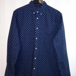 Mörkblå paisleymönstrad skjorta Bondelid - Snygg mörkblå skjorta från Bondelid med vitt paisleymönster. Skjortan har klassisk krage, knäppning framtill och en bröstficka. Tillverkad i bomull och har en skräddad passform som sitter riktigt bra. Perfekt för dig som gillar stilrena detaljer. Kan skickas med extra pris via post.