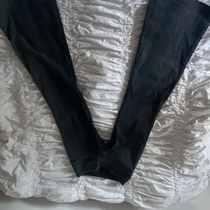 Lågmidiade bootcutjeans  - Snygga svarta jeans med tre coola metallknappar i midjan. Jeansen har en smal passform och är tillverkade i ett stretchigt material. Perfekta för dig som gillar en stilren och modern look. Det står att den är  S, men jag skulle säga att de är XS, köpt för 400 för inte så länge sen men jag har använt de väldigt få gånger för de är för små för mig